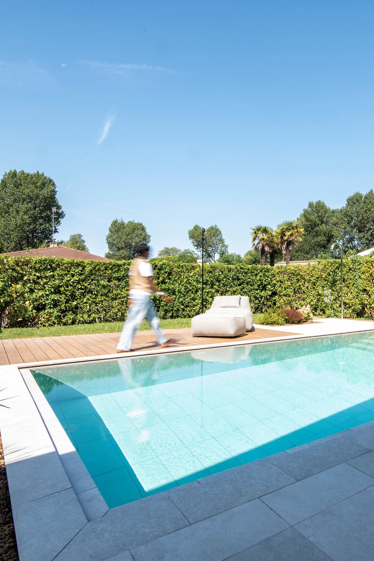 Piscina con zona relax a bordo vasca e percorso pavimentato nel giardino