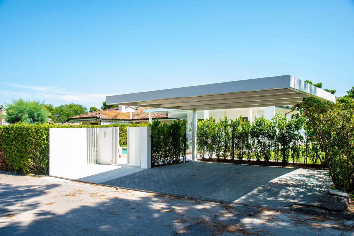 Ingresso alla proprietà con posto auto coperto e accesso schermato verso il giardino