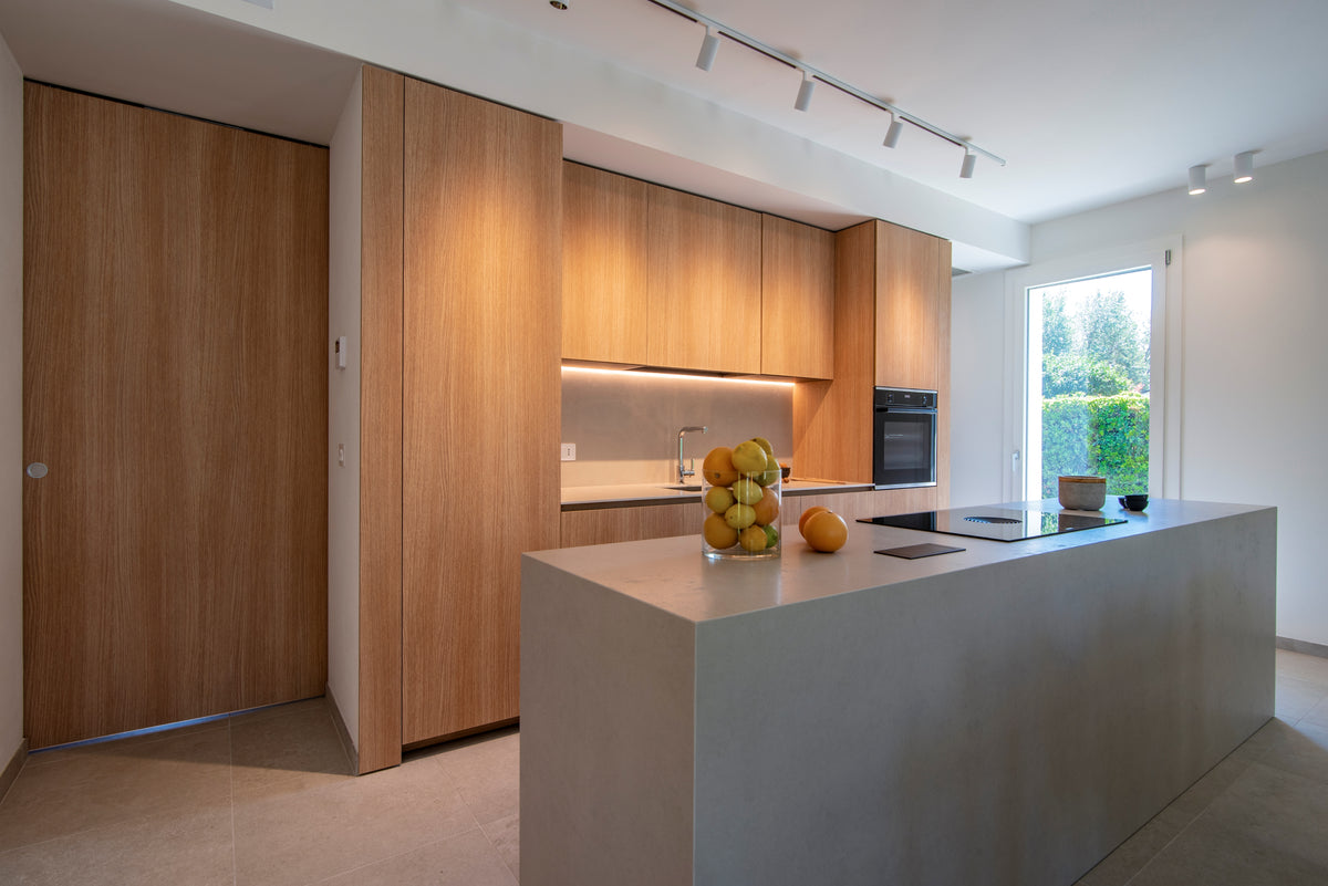 Cucina su misura in legno con isola centrale e volumi integrati nel progetto di interior design di Casa AM