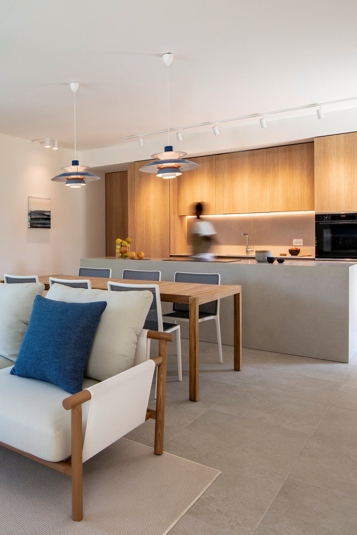 Living con divano chiaro, tavolo da pranzo e cucina in legno sullo sfondo