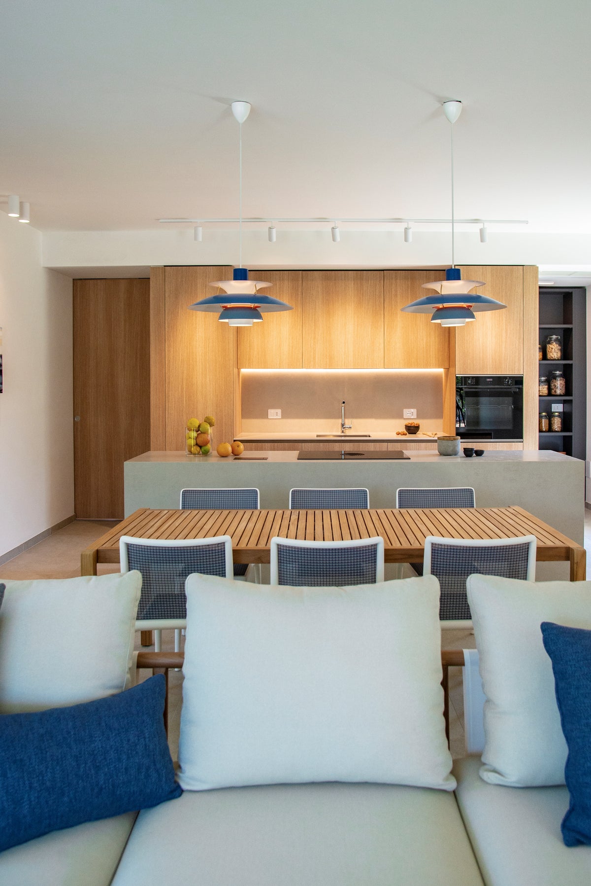 Vista frontale dell’open space con living, tavolo da pranzo e cucina su misura in legno