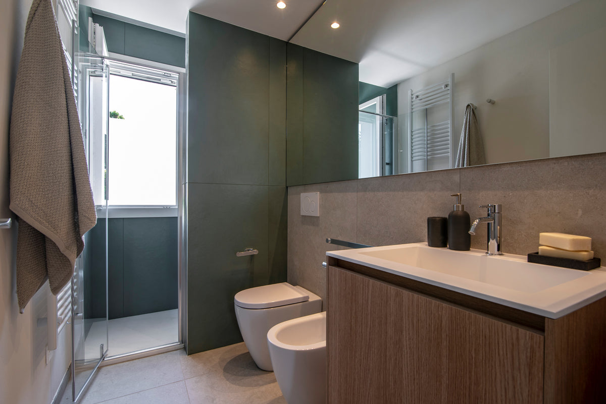 Bagno contemporaneo con doccia in vetro, mobile lavabo in legno e rivestimenti verde scuro e grigio