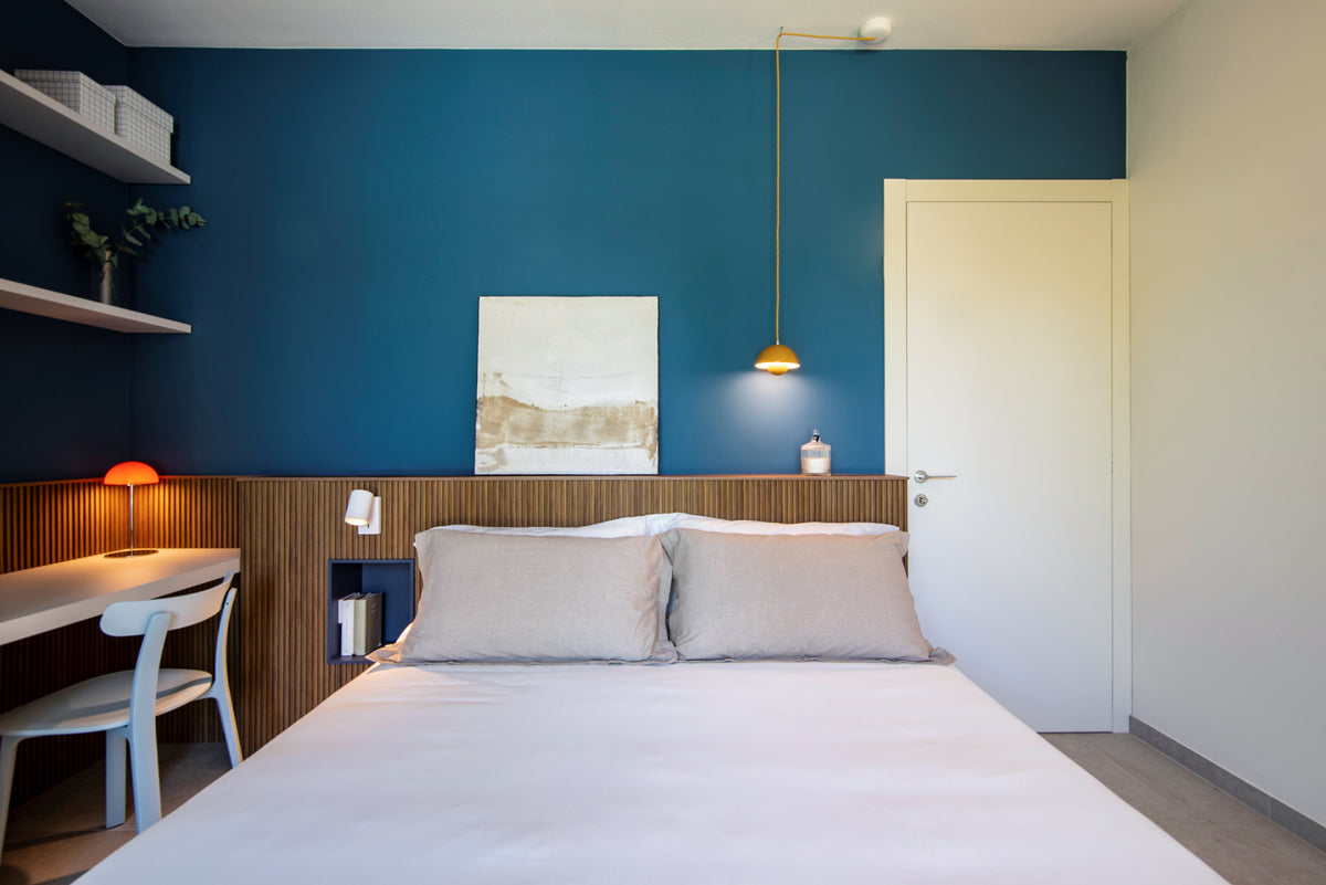 Terza camera da letto con boiserie retro letto in legno, parete blu, scrittoio integrato e arredi su misura