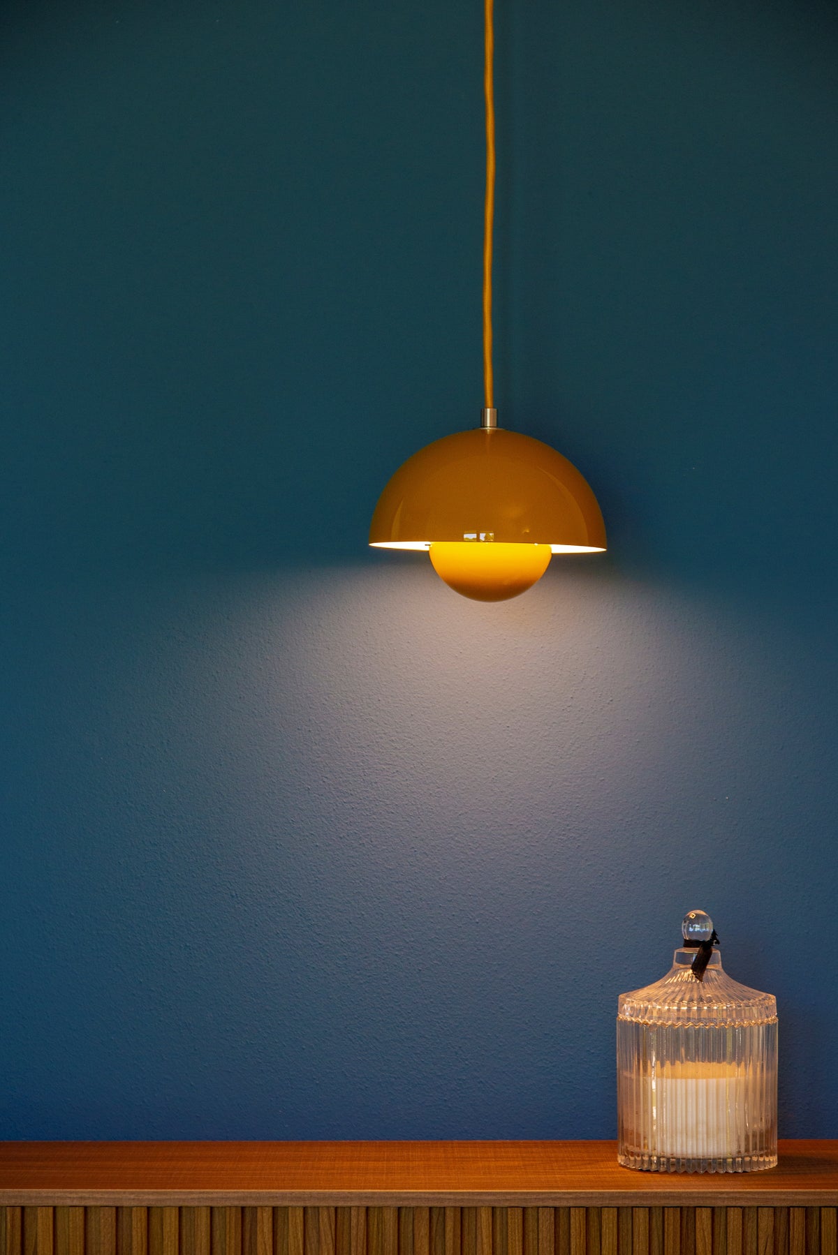 Dettaglio della lampada a sospensione gialla sulla parete blu della camera da letto