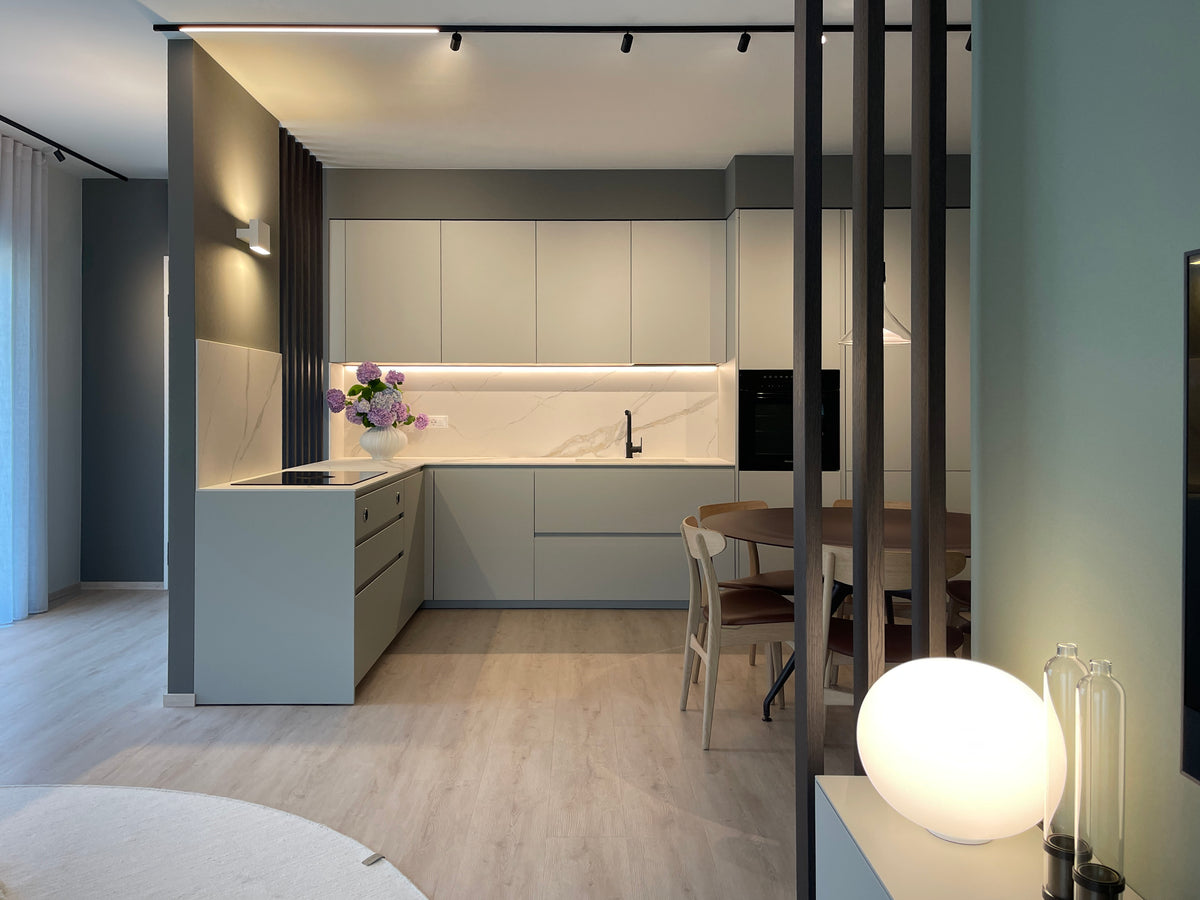 Vista della zona giorno con cucina ad angolo su misura, tavolo da pranzo rotondo e divisorio a listelli in legno