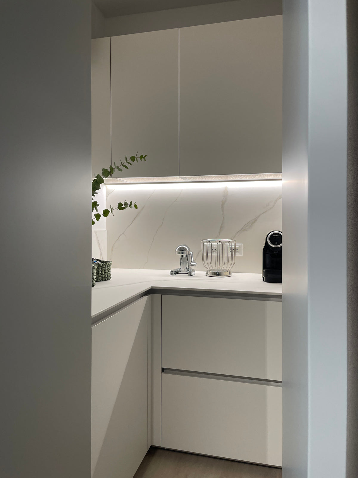 Vano tecnico nascosto accessibile dalla cucina con piano di lavoro, armadiature contenitive e piccoli elettrodomestici