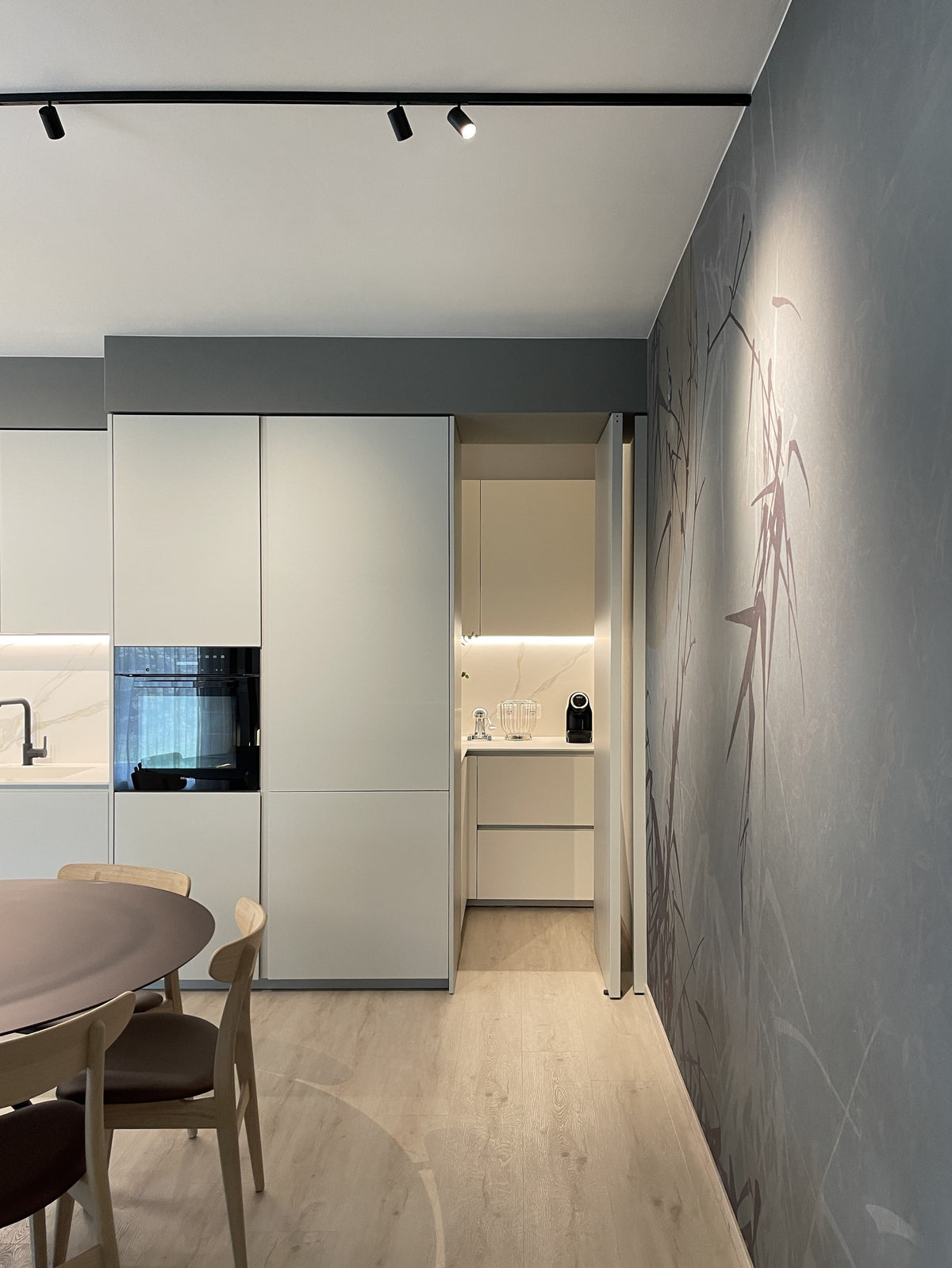 Dettaglio della porta pivot aperta che introduce alla zona di servizio nascosta accanto alla cucina