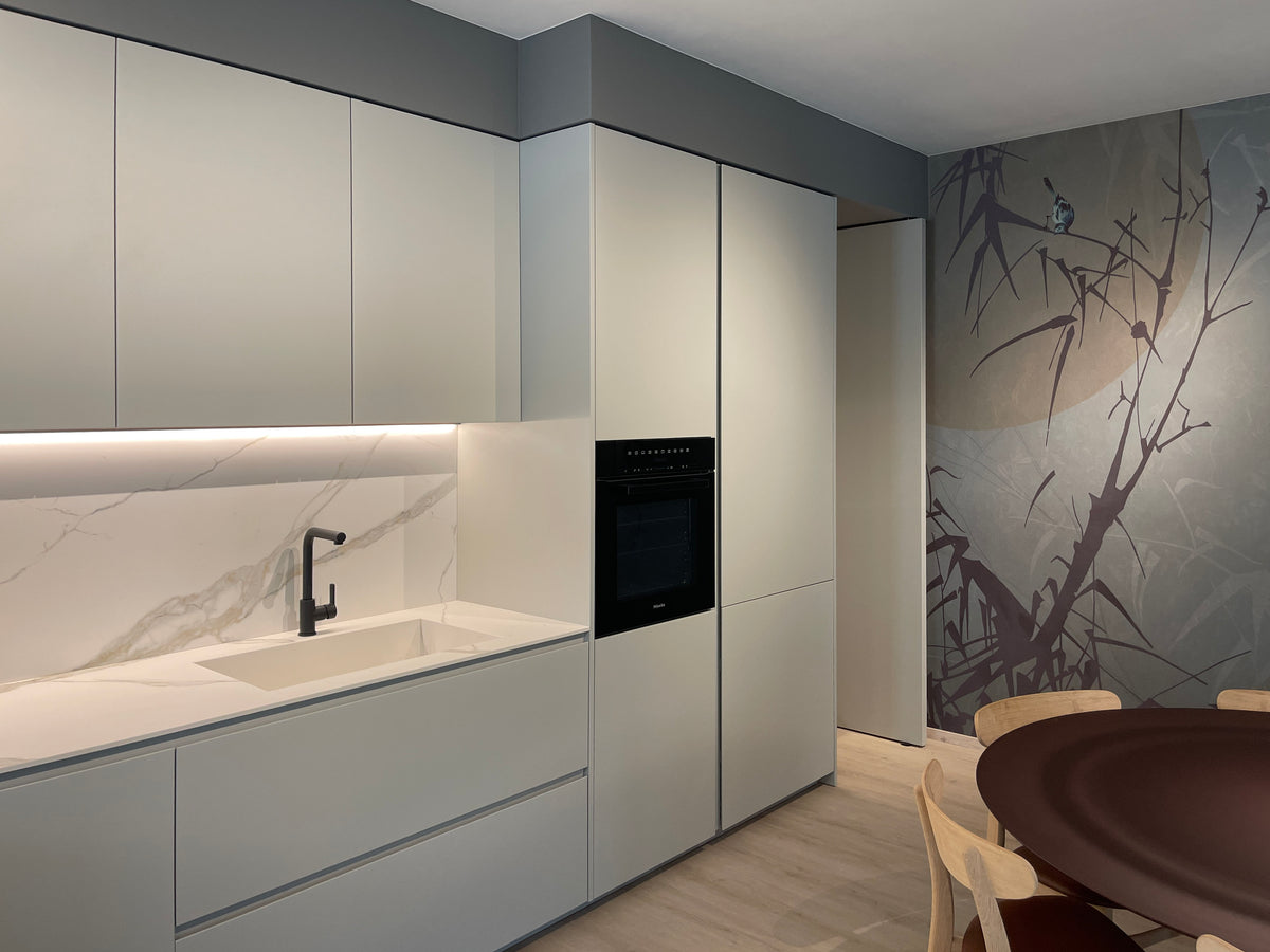Dettaglio della cucina con lavello integrato, colonne contenitive e carta da parati decorativa della zona pranzo