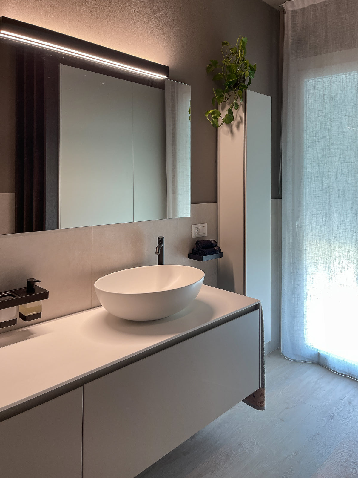 Bagno moderno su misura in casa di nuova costruzione, con mobile sospeso, lavabo da appoggio e specchio illuminato