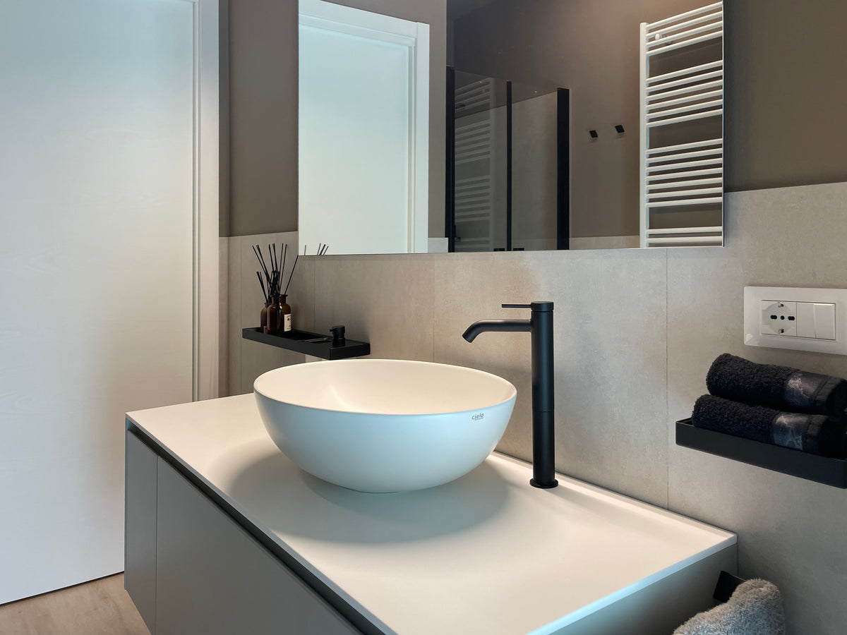 Bagno residenziale moderno con lavabo da appoggio, rubinetteria nera, top bianco e grande specchio a parete