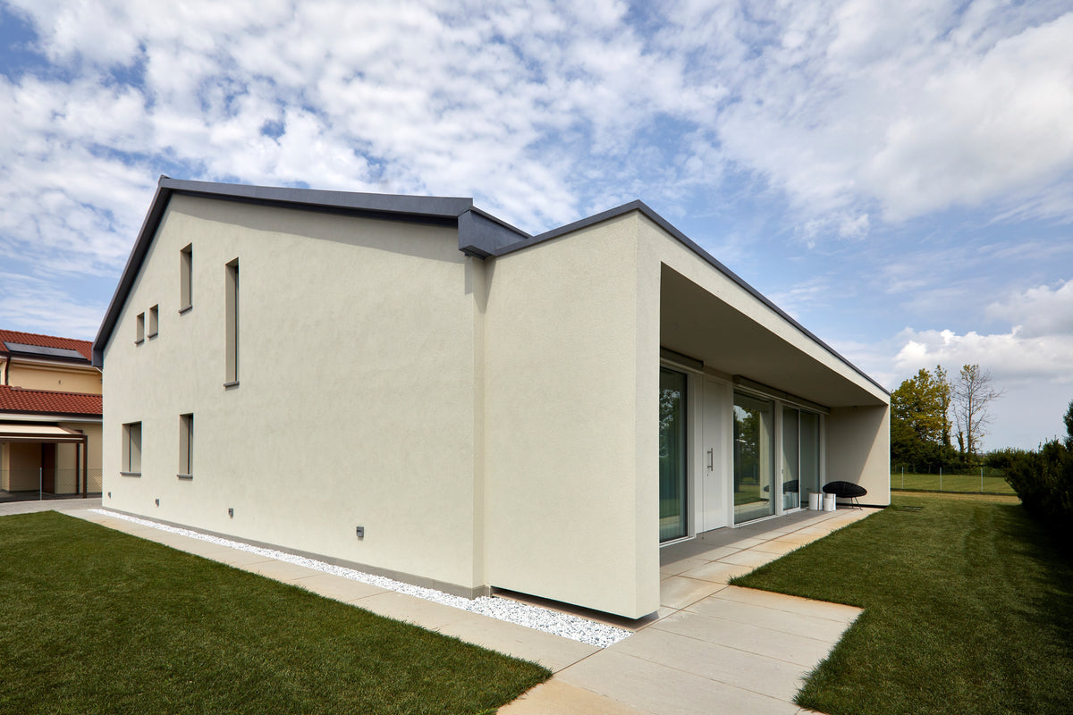 Esterno della casa con portico lineare, grandi aperture e rapporto tra interno ed esterno
