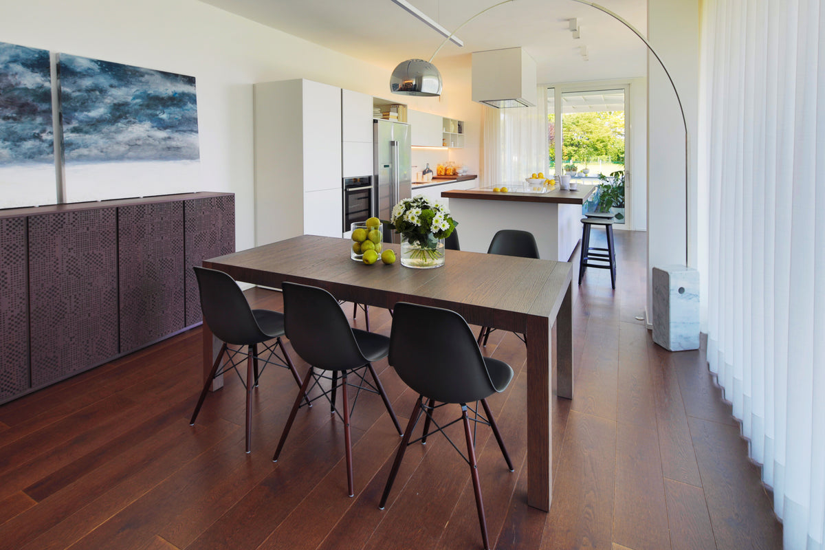 Zona giorno open space con tavolo, cucina bianca con isola e grandi vetrate su due lati in un progetto residenziale contemporaneo