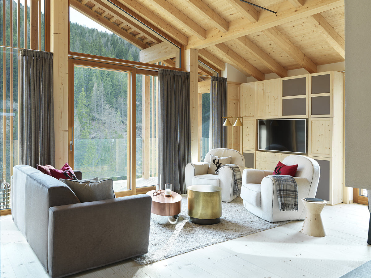 Living luminoso con divano, poltrone arrotondate e ampie vetrate sulle Dolomiti, interior design contemporaneo