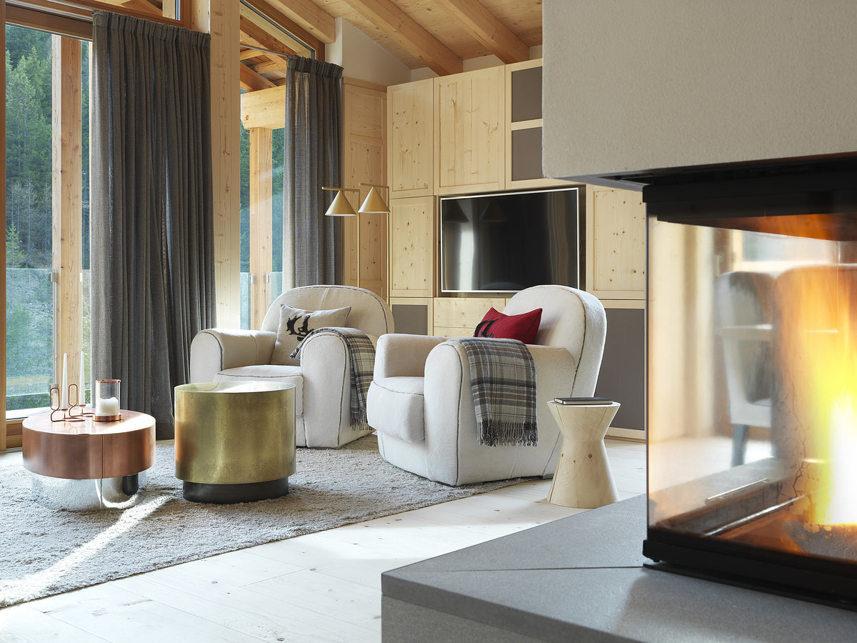 Area living con camino contemporaneo e poltrone in montone chiaro, atmosfera calda in chalet di montagna