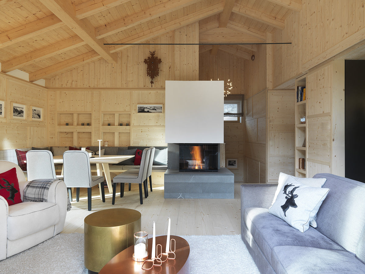 Open space con soggiorno, zona pranzo e camino moderno, in ambiente caldo con soffitto in travi di legno