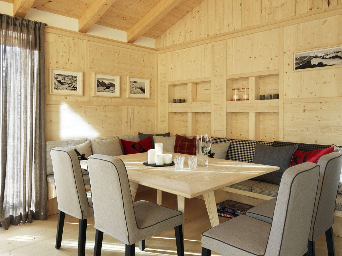 Sala da pranzo con tavolo in legno e sedute imbottite, continuità tra arredi e rivestimenti