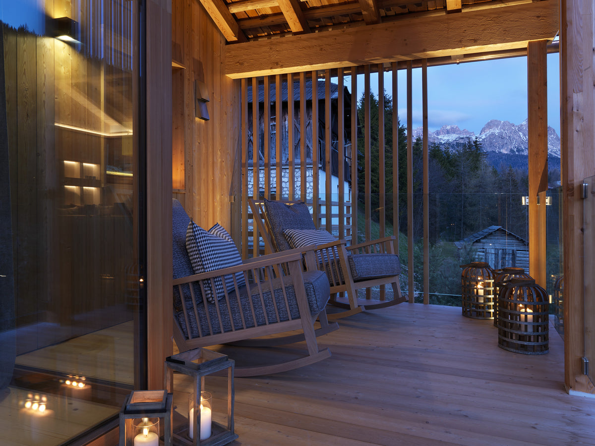 Terrazza coperta con seduta a dondolo e vista sulle Dolomiti, continuità tra interno ed esterno