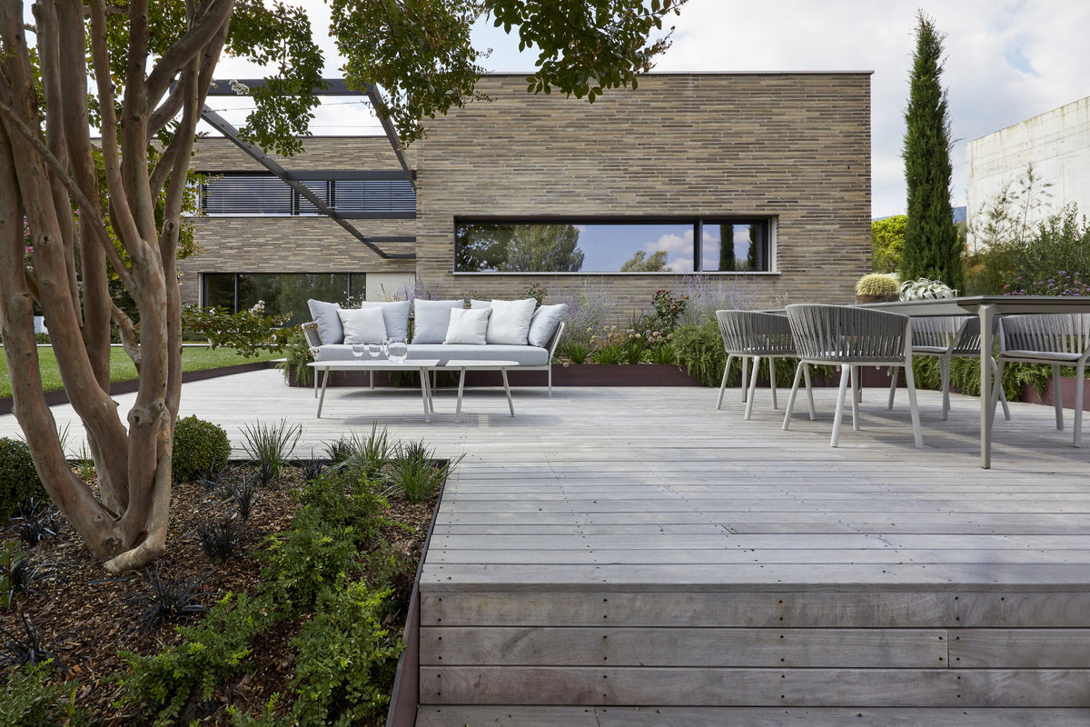 Terrazza esterna con tavolo da pranzo, giardino e volumi bassi integrati nel paesaggio