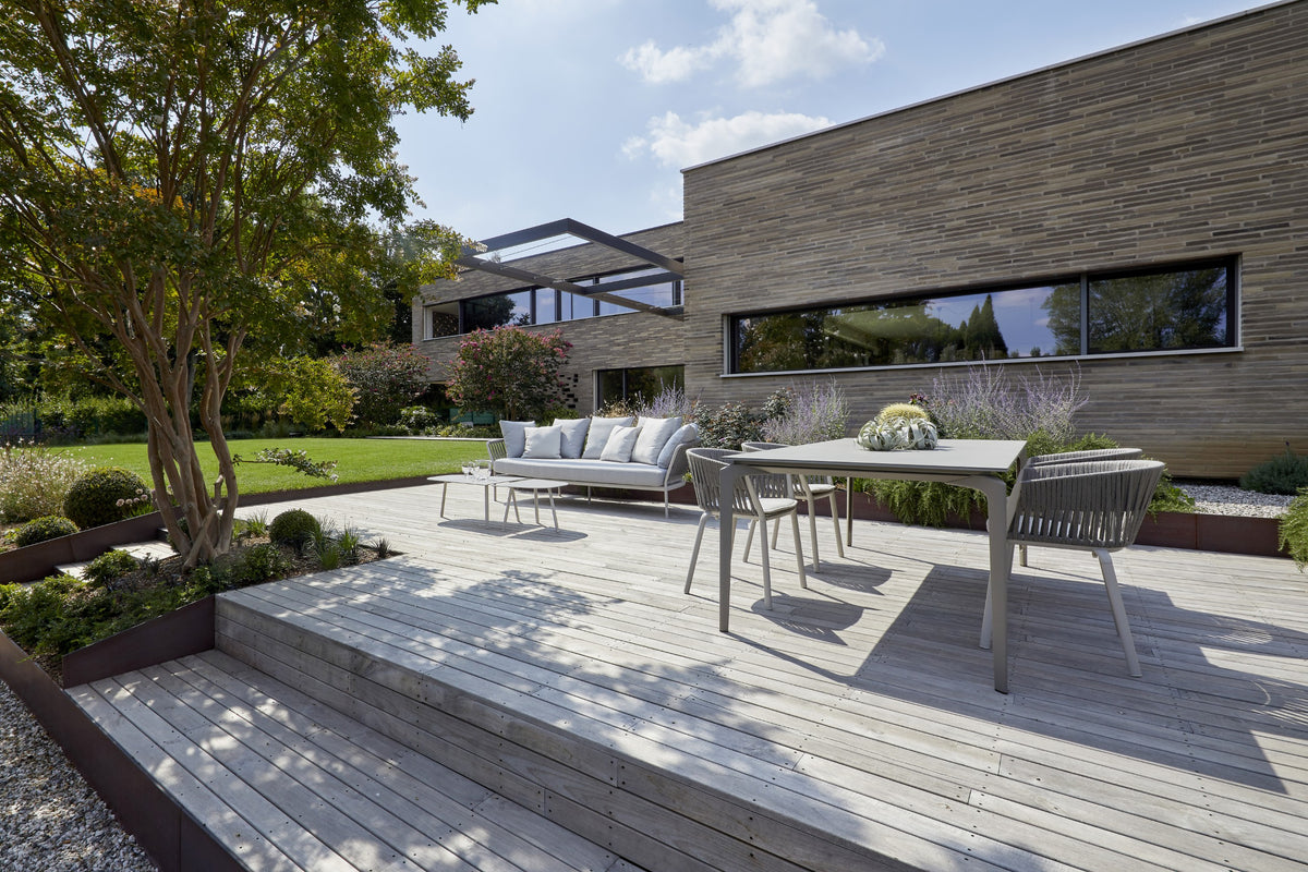 Area outdoor con deck in legno, sedute lounge e continuità tra architettura e giardino
