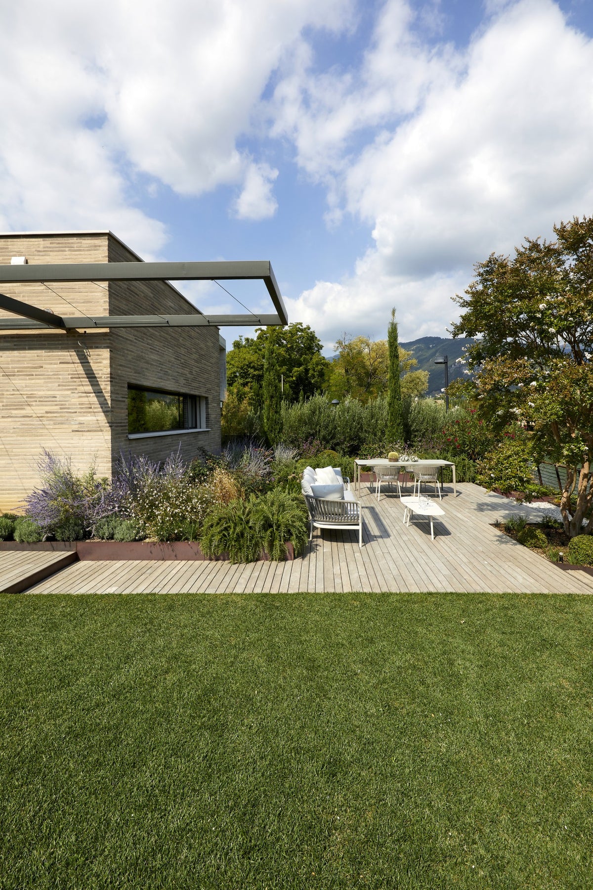 Vista del giardino con patio arredato e casa contemporanea immersa nel verde