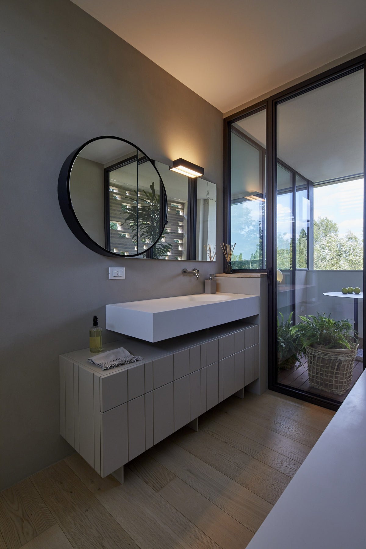 Bagno contemporaneo con mobile lavabo su misura, finiture grigie e vista sul verde