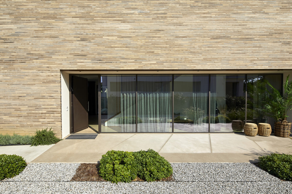 Prospetto della villa con grandi vetrate e materiali naturali