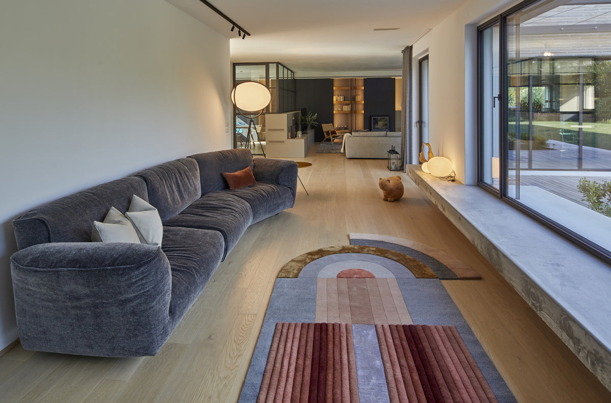 Living con grandi vetrate, divano curvo e apertura sul giardino