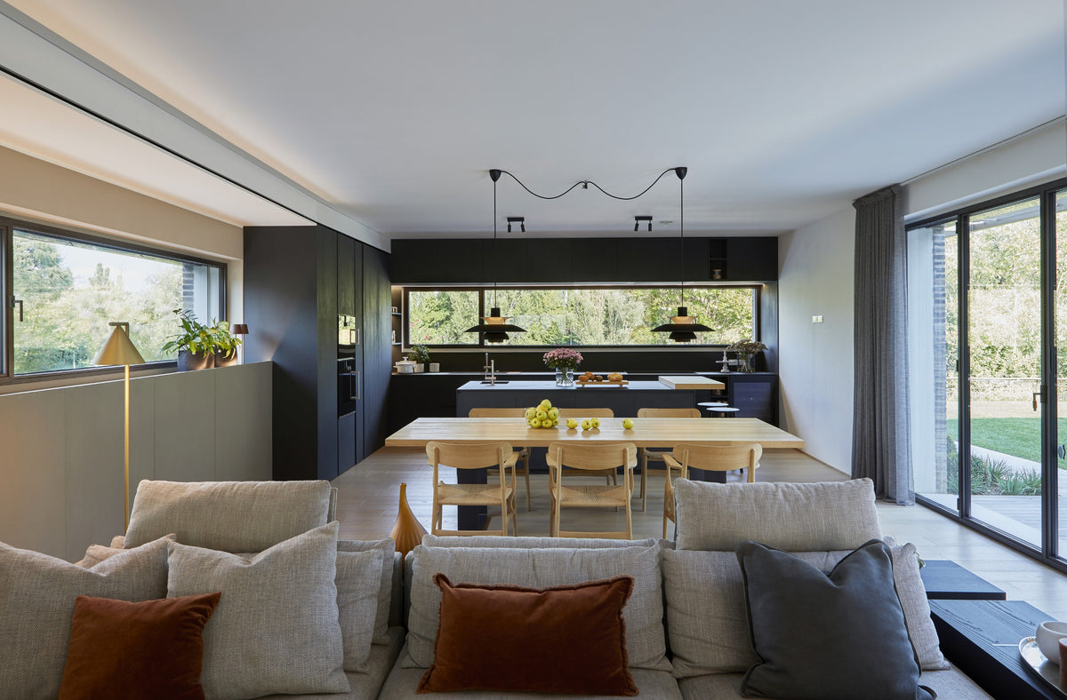 Open space con living e cucina con isola, arredamento su misura e materiali continui