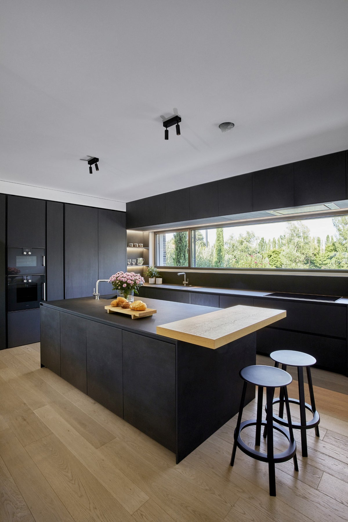 Cucina contemporanea con isola scura, finiture opache e finestra panoramica