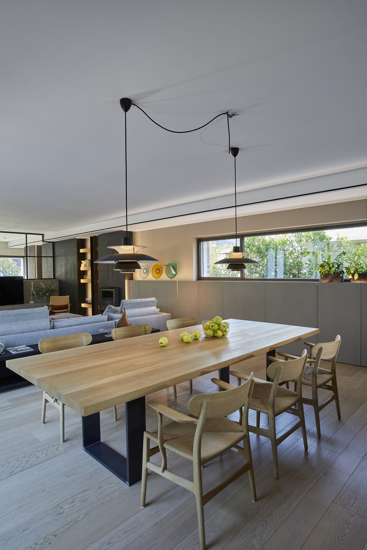 Zona pranzo con tavolo in legno chiaro e cucina aperta sul living