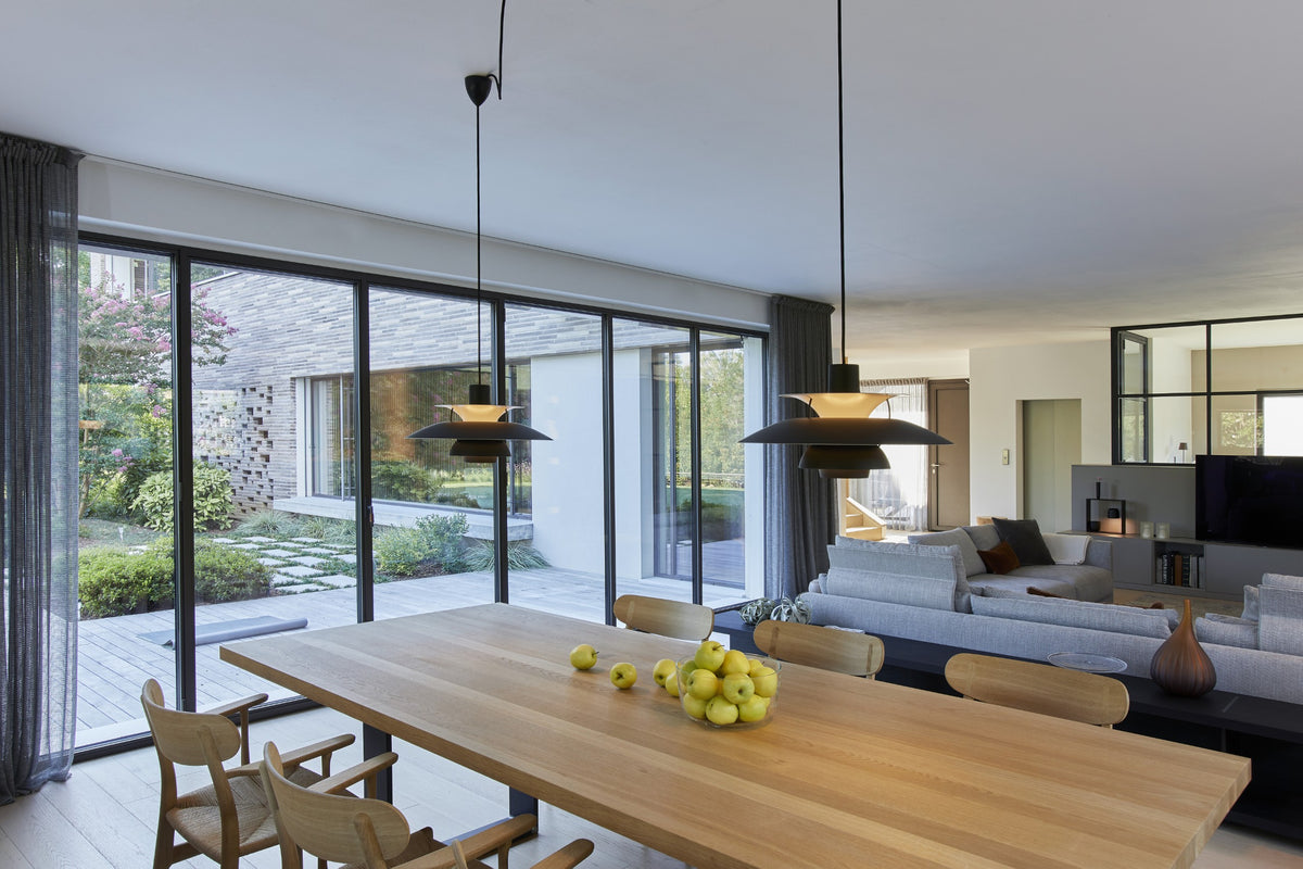 Tavolo da pranzo in legno con sospensioni di design e vetrate sul giardino