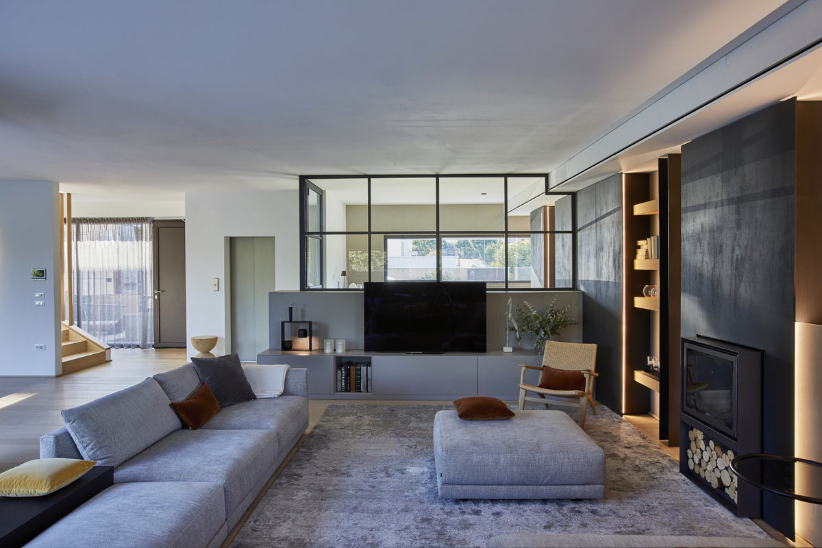 Living contemporaneo con divani chiari, parete TV e cucina aperta