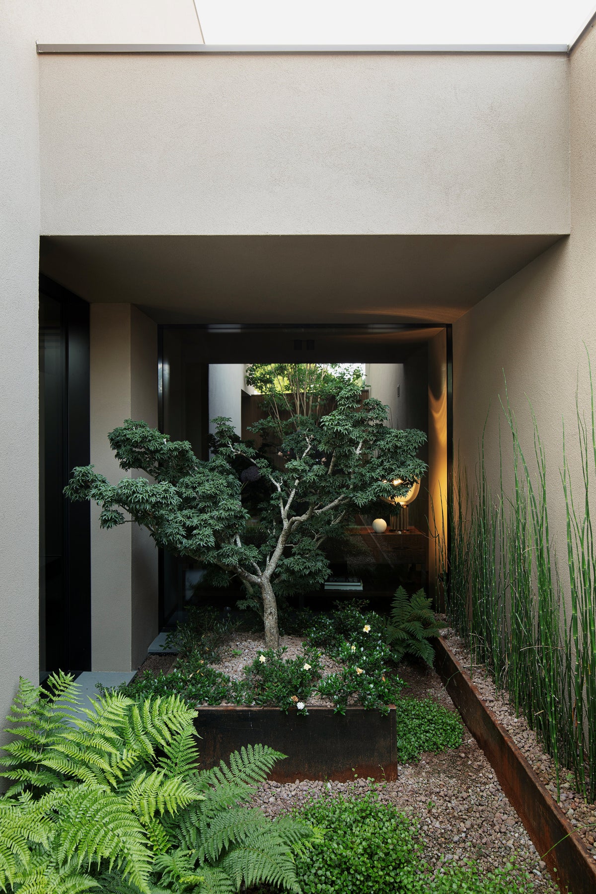 Ingresso coperto con giardino interno e percorso architettonico essenziale