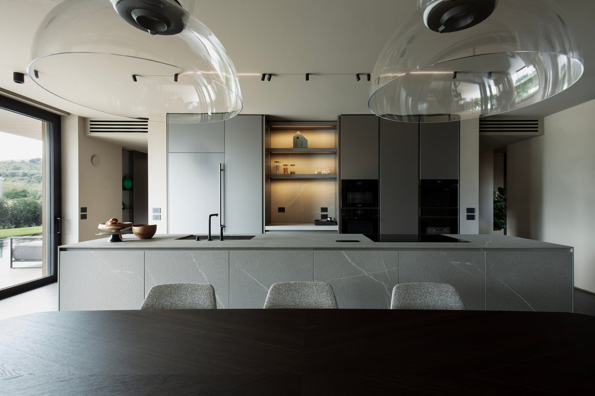 Cucina contemporanea con isola centrale Modulnova, colonne integrate e lampade in vetro