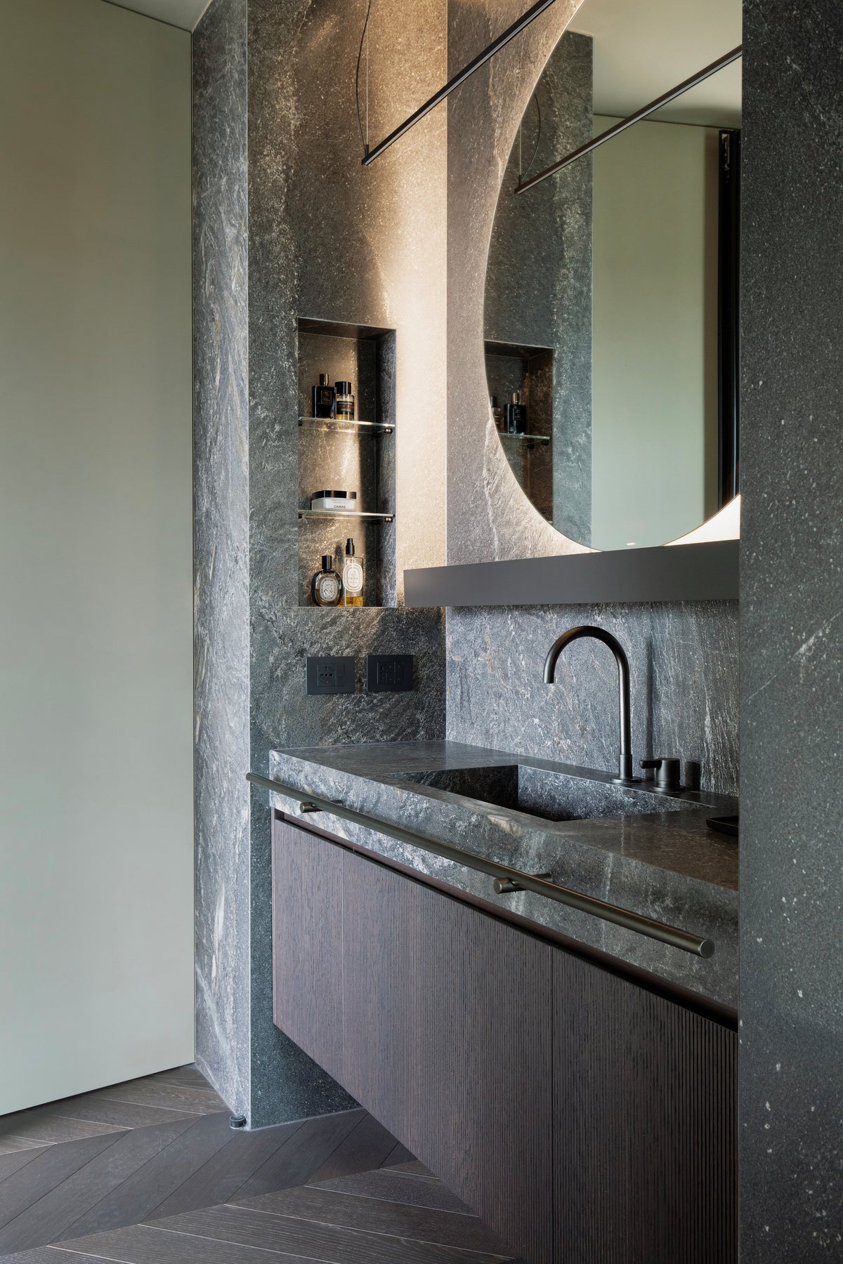 Dettaglio del bagno padronale con lavabo integrato e superfici in pietra materica