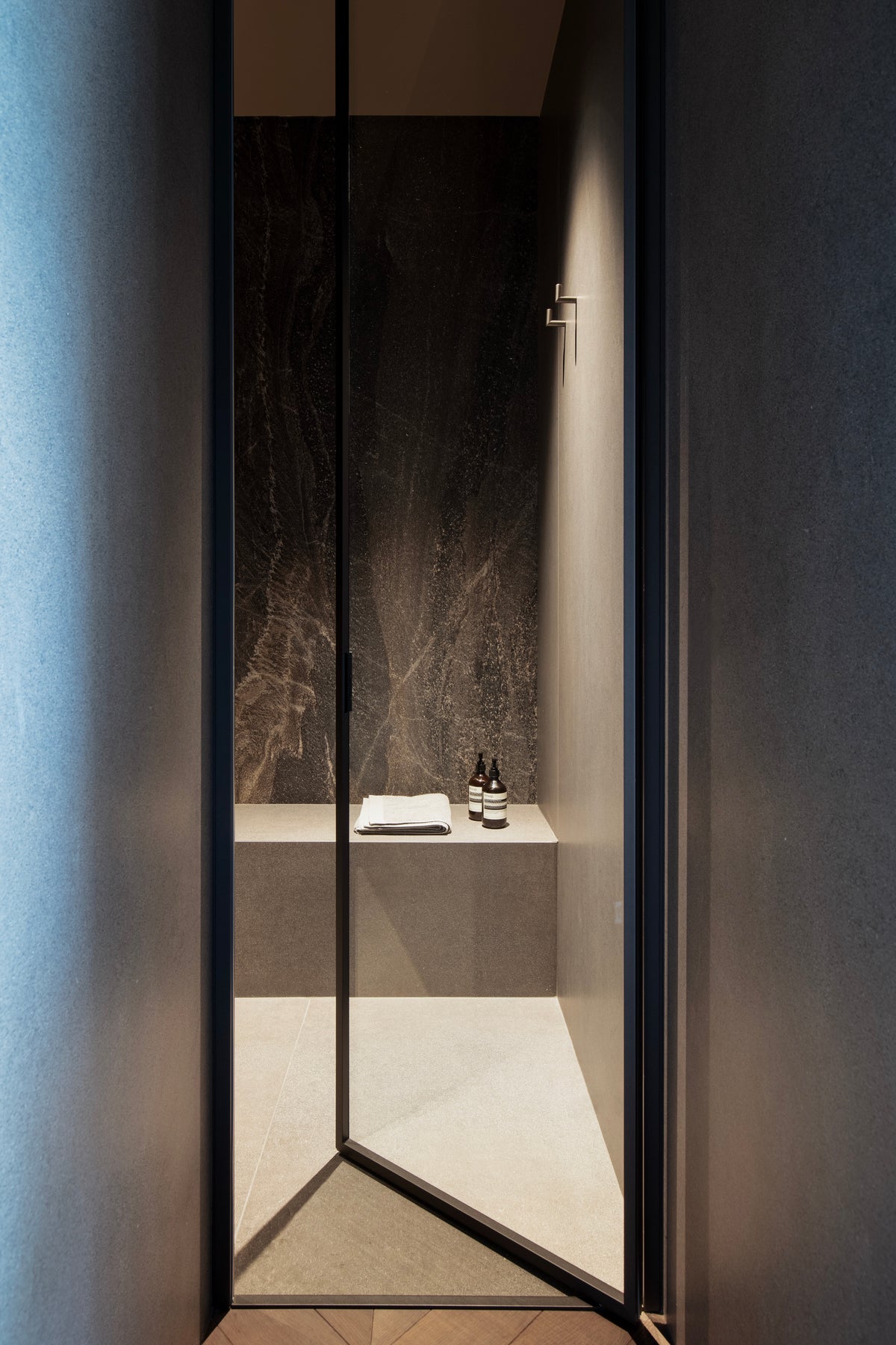Doccia walk-in con rivestimento scuro e porta in vetro trasparente