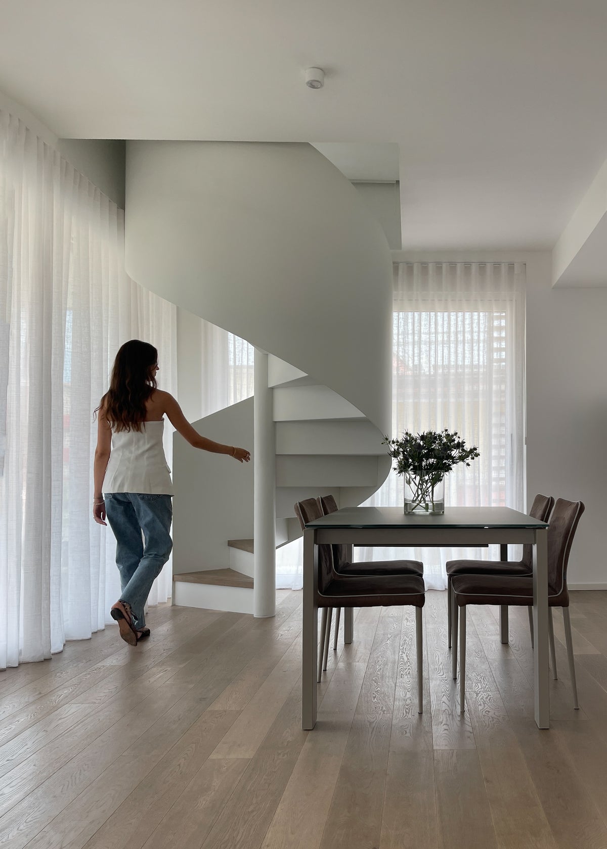 Progettazione su misura della zona giorno di un attico sul Lago di Garda con grandi vetrate e scala a chiocciola di design