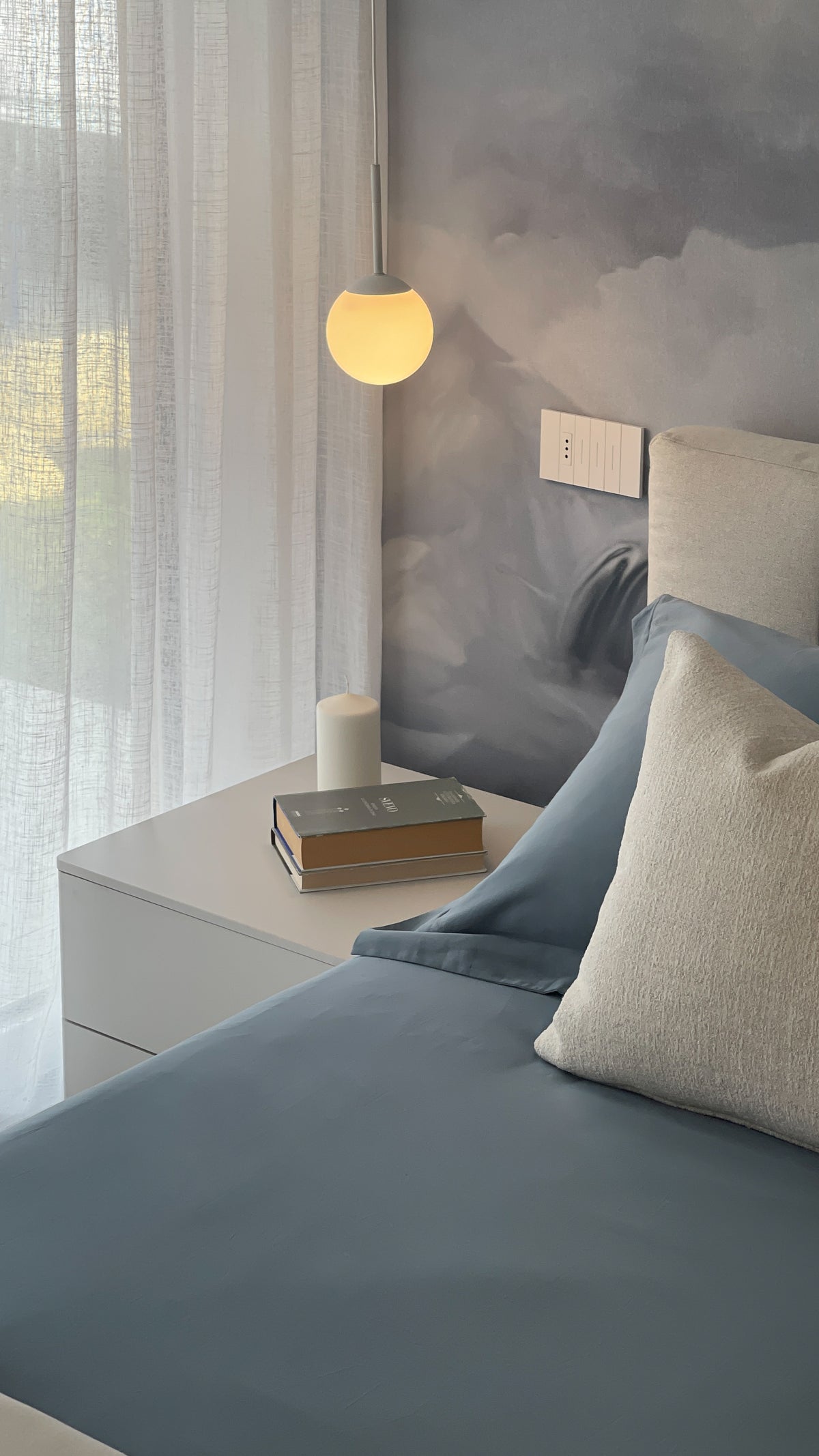Camera da letto contemporanea con arredi chiari, tessili azzurri e carta da parati panoramica