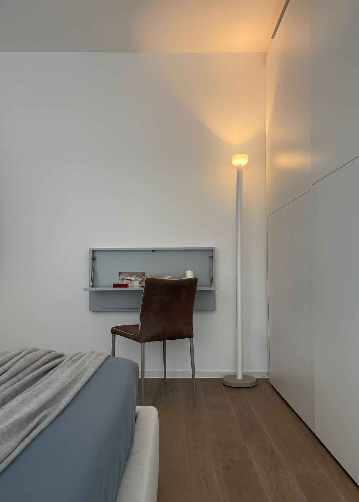 Angolo studio integrato nella camera da letto con scrittoio a parete e illuminazione da terra