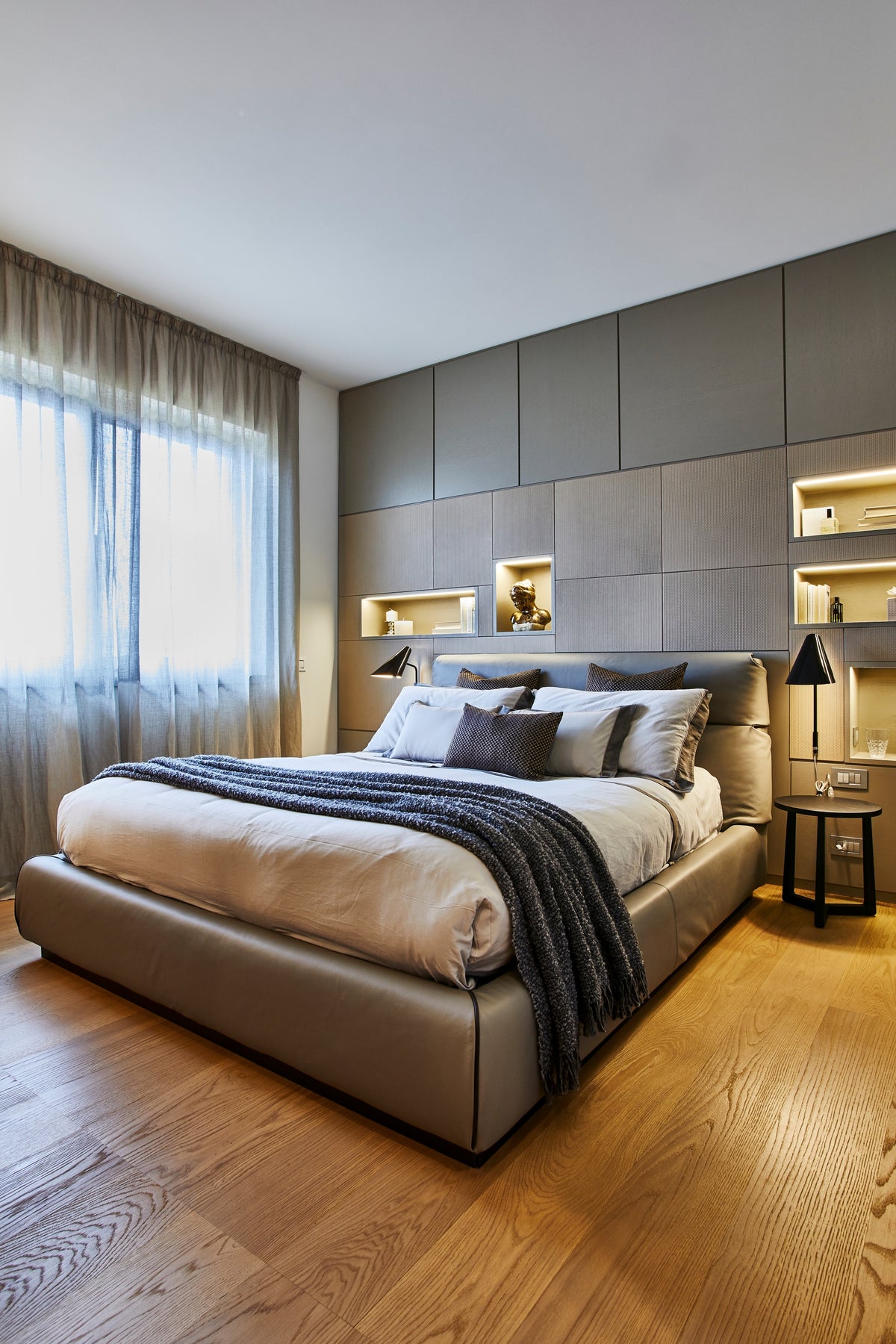 Camera padronale moderna con letto in pelle, testata attrezzata, nicchie illuminate integrate e boiserie moderna di design