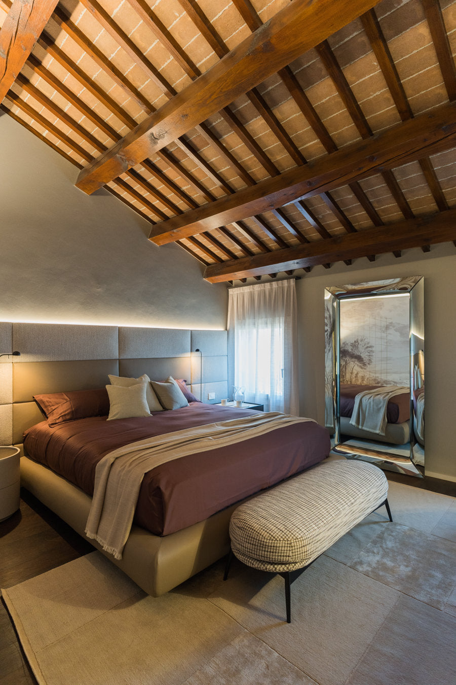 Camera padronale con letto tessile, specchio da terra e soffitto in legno originale restaurato