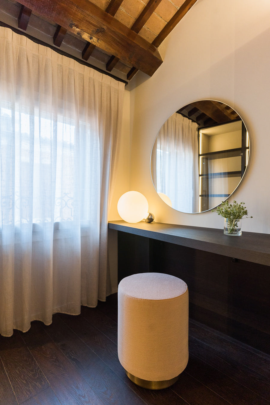 Angolo della cabina armadio con specchio rotondo, tavolino e luce morbida