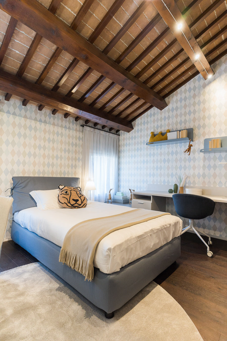 Camera bambino con letto tessile e soffitto con travi in legno
