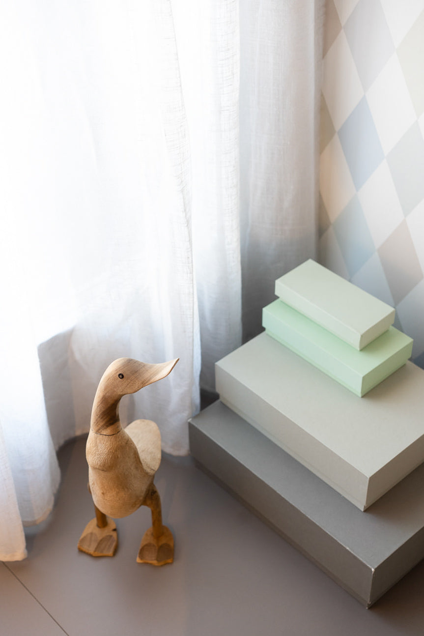 Dettaglio decorativo della cameretta con tendaggio chiaro e giochi in legno