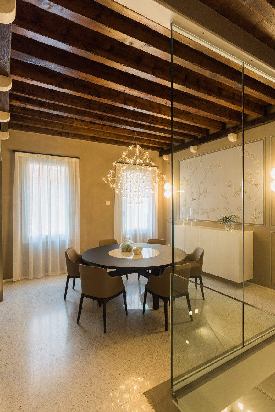 Sala da pranzo in casa storica ristrutturata con lampadario scenografico e tavolo rotondo