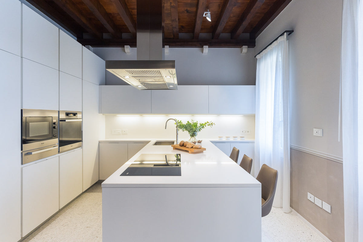 Cucina lineare bianca con isola centrale e soffitto in legno originale