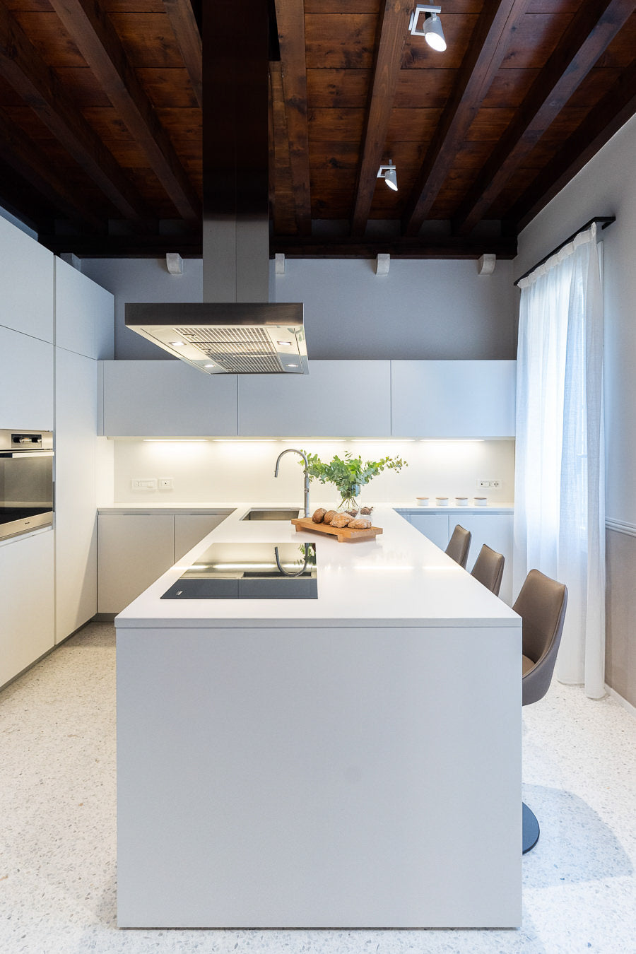 Cucina contemporanea con penisola e basi bianche e superfici essenziali