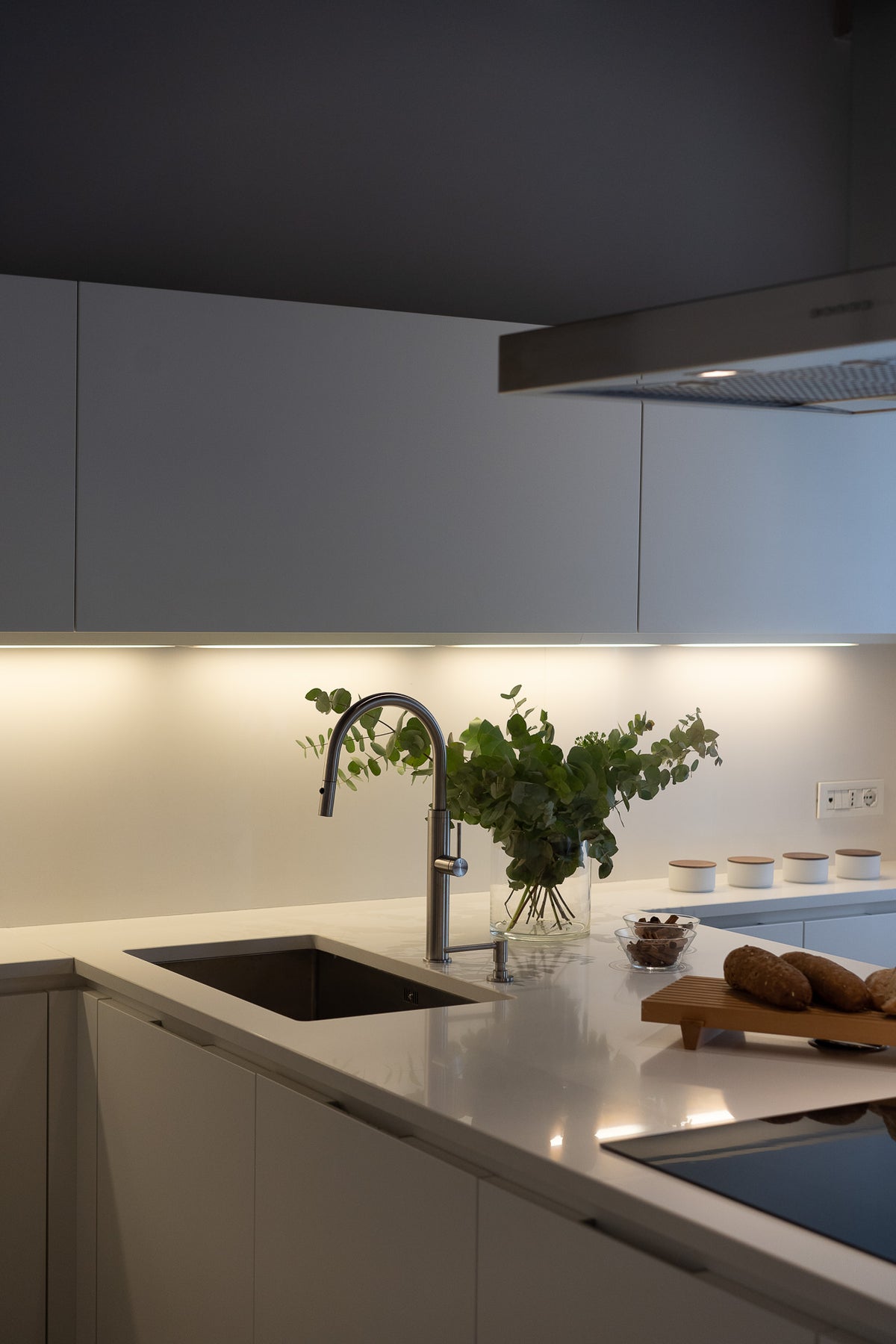 Dettaglio della cucina bianca con penisola e luce soffusa