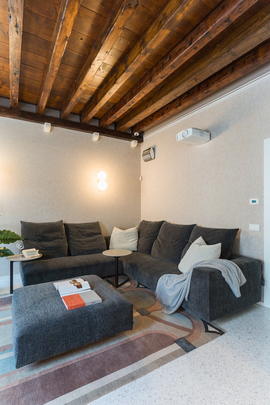 Sala relax con proiettore, divano grigio e arredi morbidi