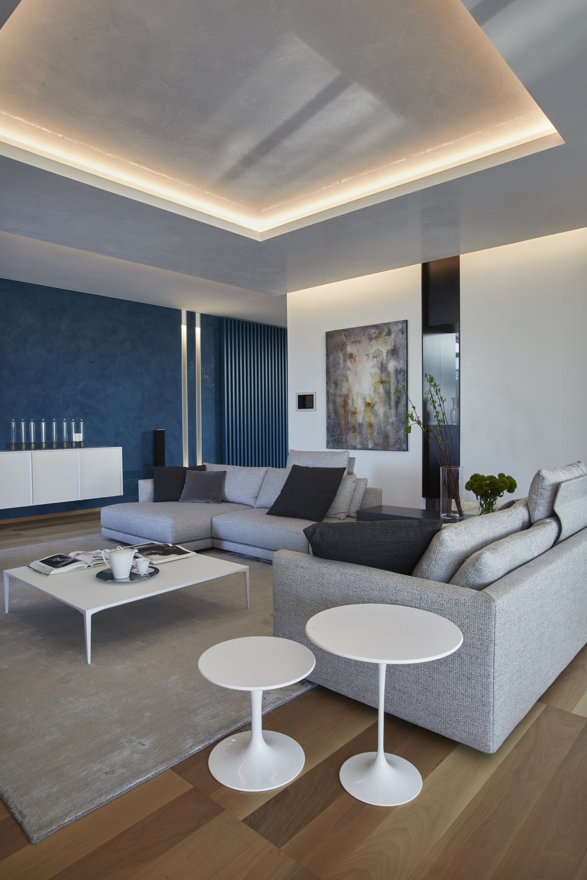 Zona living con divano componibile, tavolini bianchi e illuminazione integrata a soffitto